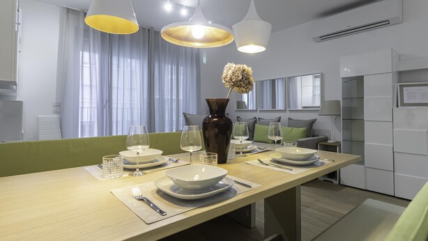 A modern dining area with a long table set for two, featuring a vase with dried flowers, a candle, and a bowl. - Italianway Comfort - Compagnoni 12 - Suite Mirabel (Milan)
