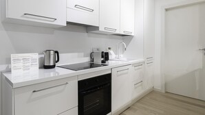 A modern kitchen with white cabinetry, a black oven, a coffee maker, and a kettle on the countertop. - Italianway Comfort - Compagnoni 12 - Suite Mirabel (Milan)