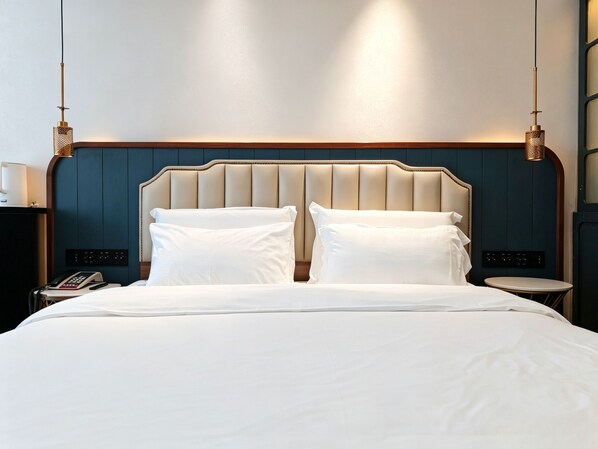 A hotel room with a large bed, two bedside tables, a nightstand, and a wall-mounted phone.
