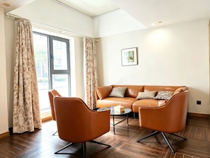 A modern living room with a leather sofa, two armchairs, a coffee table, and a large window with curtains. - Dayin International Youth Hotel (Shanghai Xinhua Road Jiaotong University Branch) (Shanghai)