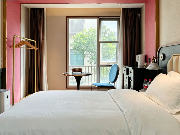 Une chambre d’hôtel avec un lit, une chaise, une table et une fenêtre donnant sur des arbres.