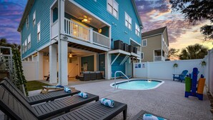 Une maison à deux étages dotée d’une piscine, d’un espace salon extérieur et d’un patio couvert.