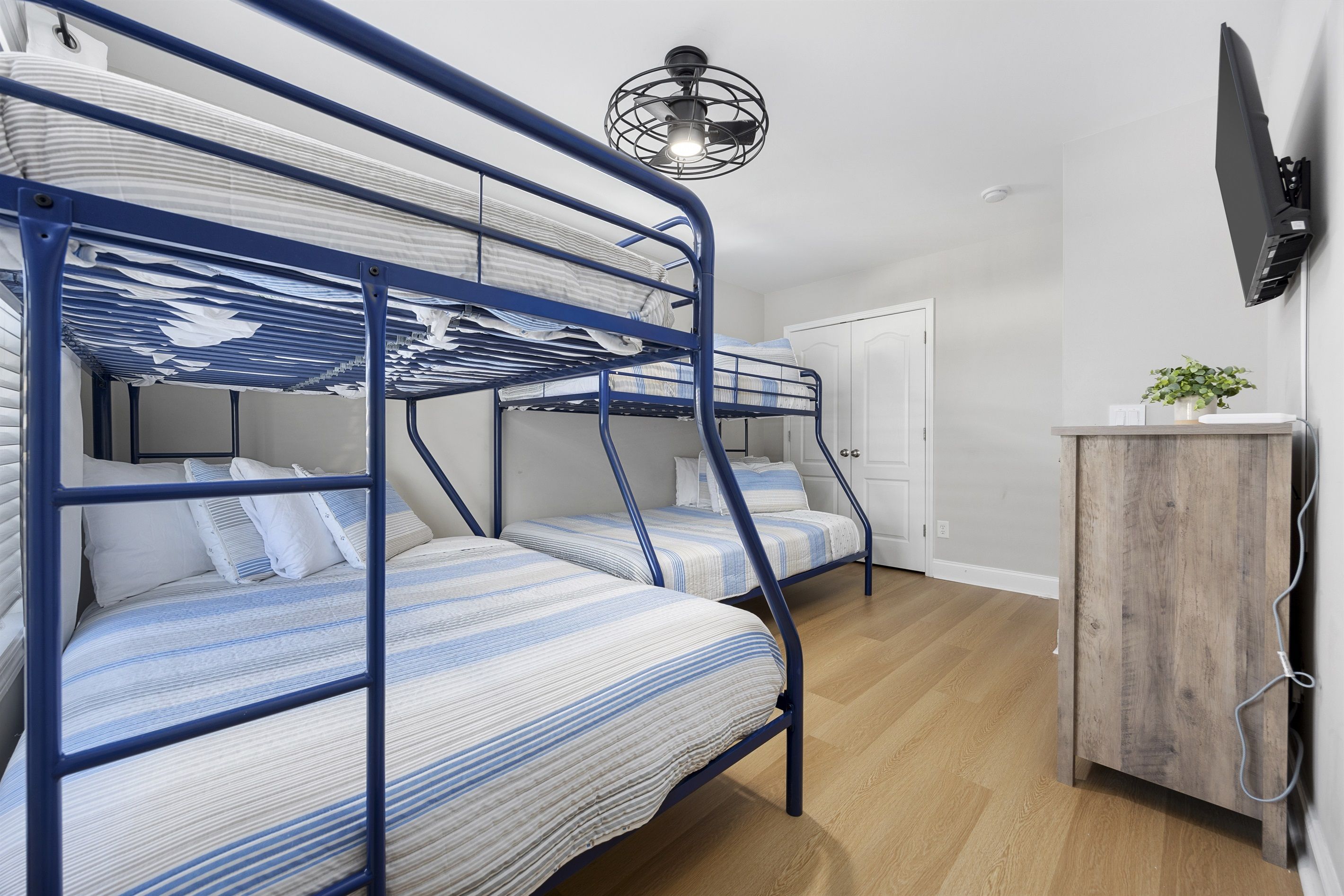 A bunk bed room with a wooden cabinet and a flat-screen TV.
