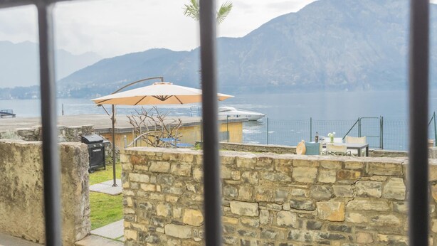 A stone wall with a patio area, a grill, and outdoor furniture.