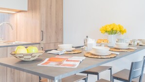 A modern kitchen with wooden cabinets, a central island with a vase of yellow flowers, and a bowl of lemons.