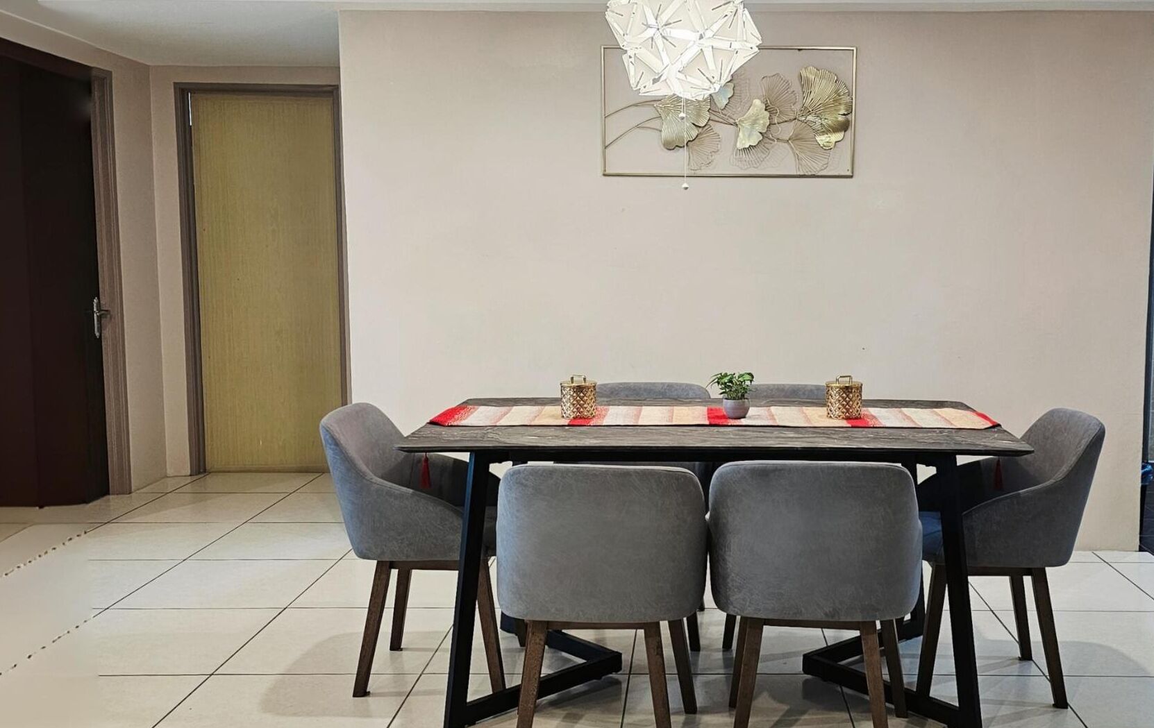 Un espace repas comprenant une table rectangulaire, six chaises grises et un élément décoratif mural au-dessus.