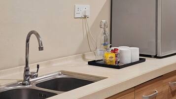 A kitchen with a double sink, a coffee maker, and a tray with coffee cups and condiments.