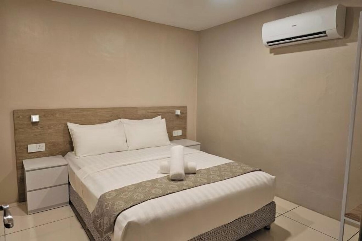 A neatly made bed with a headboard, a bedside table, and an air conditioning unit on the wall.