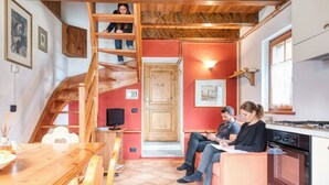 A cozy interior with a wooden staircase, a dining area, a kitchen, and a red accent wall.