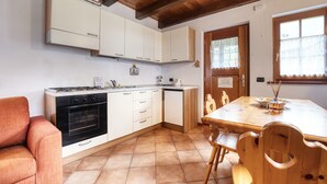 A kitchen with white cabinets, a stove, and a dining table with chairs.