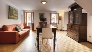 A living room with a sofa, a dining table with chairs, a TV, and a cabinet.