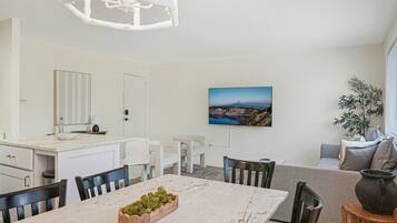 A modern kitchen with white cabinetry, a marble countertop, and a dining area with a marble table and chairs.