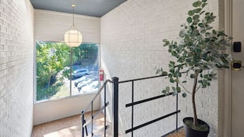 A staircase with a black railing, a potted plant, and a hanging light fixture.