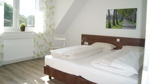 Une chambre à coucher avec un lit, une fenêtre donnant sur un beau paysage, un radiateur et un tableau accroché au mur.