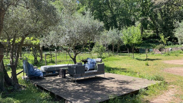 A rustic outdoor seating area with a wooden deck, metal chairs, and a bench.
