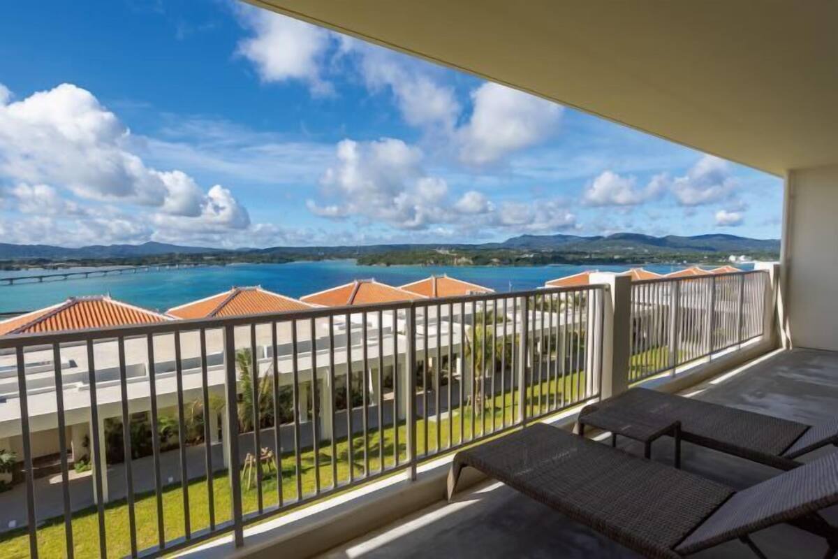 Un balcon offrant une vue sur une zone côtière, avec notamment un pont et des bâtiments aux toits rouges.