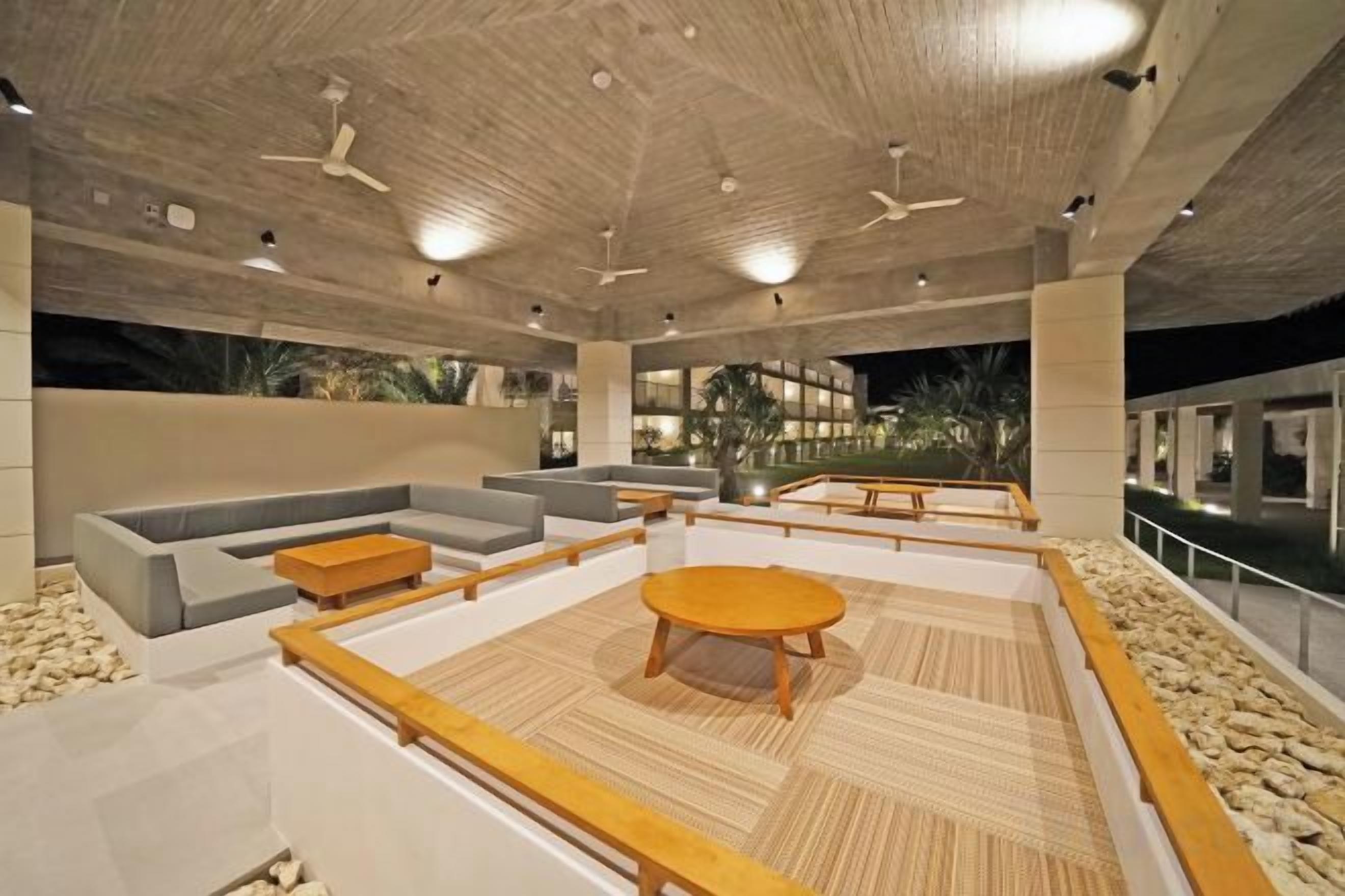 An indoor lounge area with seating arrangements, a central coffee table, and a ceiling fan.