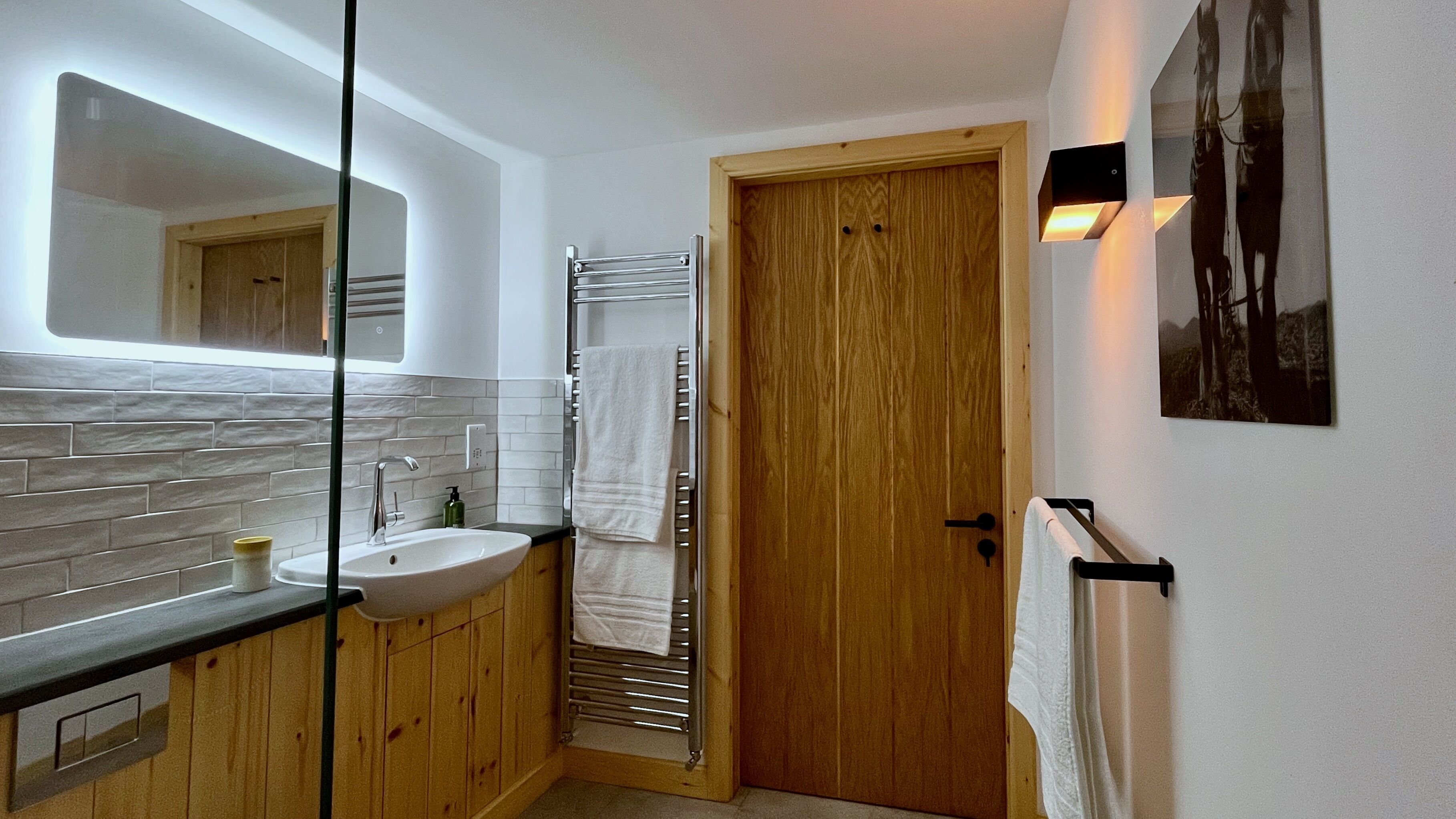 A bathroom with a wooden vanity, a sink, a mirror, and a towel rack.
