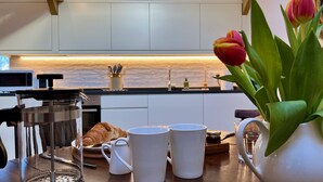A modern kitchen with a coffee maker, croissant, and two white mugs on the counter. - Cambrian Cottages (Pencader)