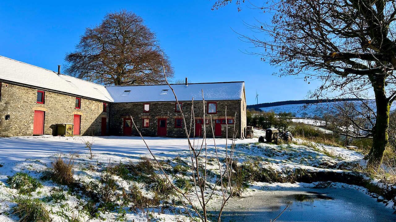 A stone building with red doors and a snow-covered landscape.