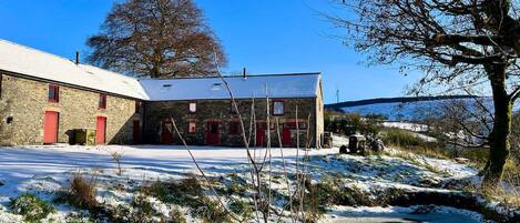 A stone building with red doors and a snow-covered landscape.