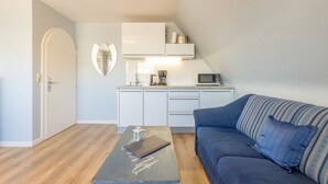 A compact living space with a kitchenette, a sofa, and a coffee table.