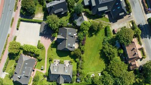 An aerial view of a residential area with multiple houses, a parking lot, and a road.