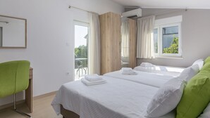 Ein modernes Hotelzimmer mit einem großen Bett, einem grünen Sessel, einem Holzschrank und einem Balkon mit Blick.