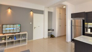 A modern kitchen with a built-in refrigerator, a TV on a white console, and a grey wall. - Athenian Riviera Vari next to the beach (Vari)