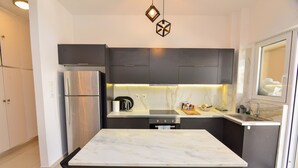 A modern kitchen with dark cabinets, a stainless steel refrigerator, a marble countertop, and a built-in oven. - Athenian Riviera Vari next to the beach (Vari)