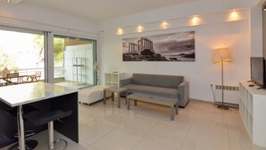 A modern living room with a sofa, two coffee tables, a TV, and a painting of ancient ruins. - Athenian Riviera Vari next to the beach (Vari)