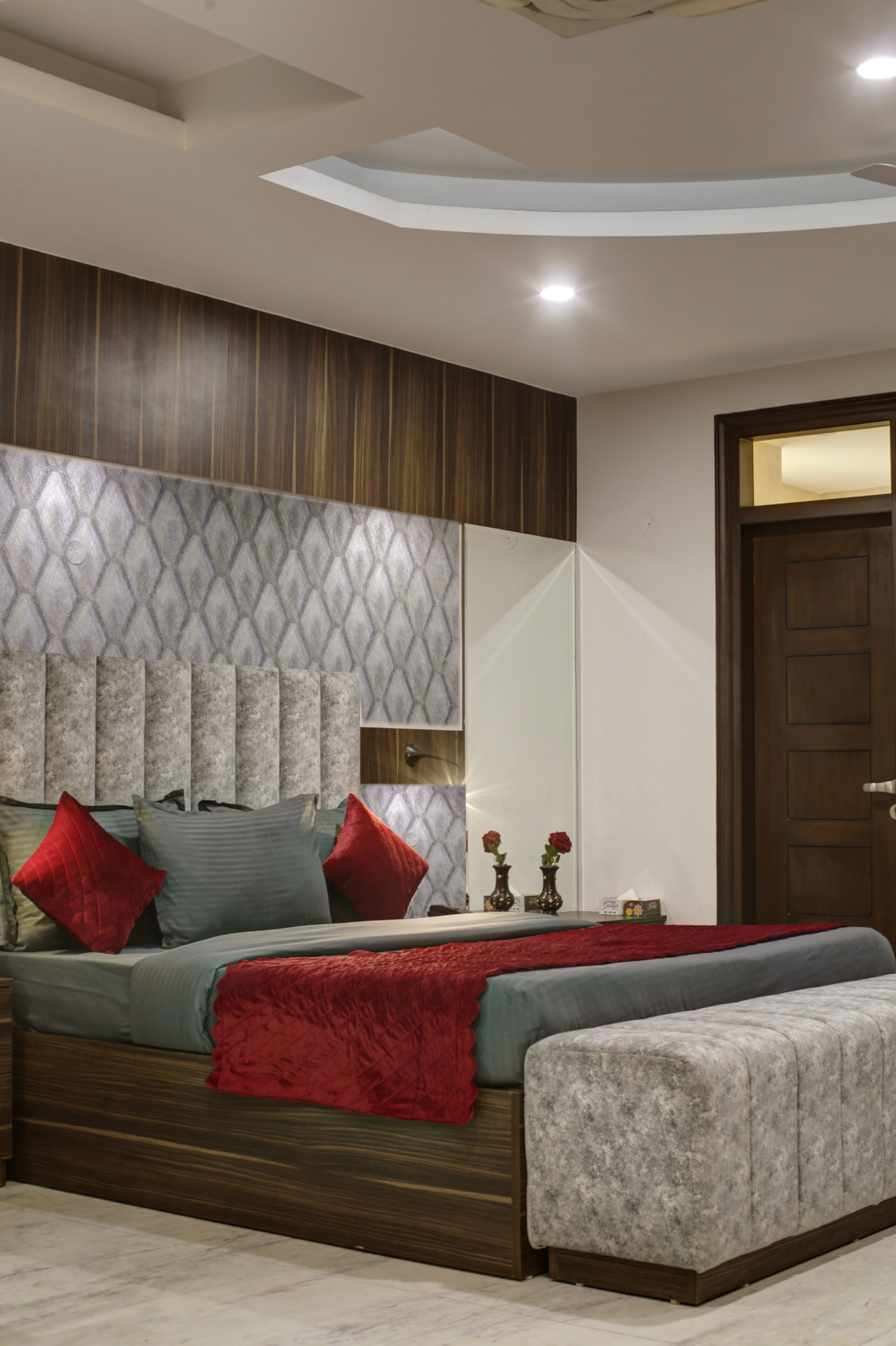 Un dormitorio moderno con una cama grande, un cabecero de madera y un espejo.