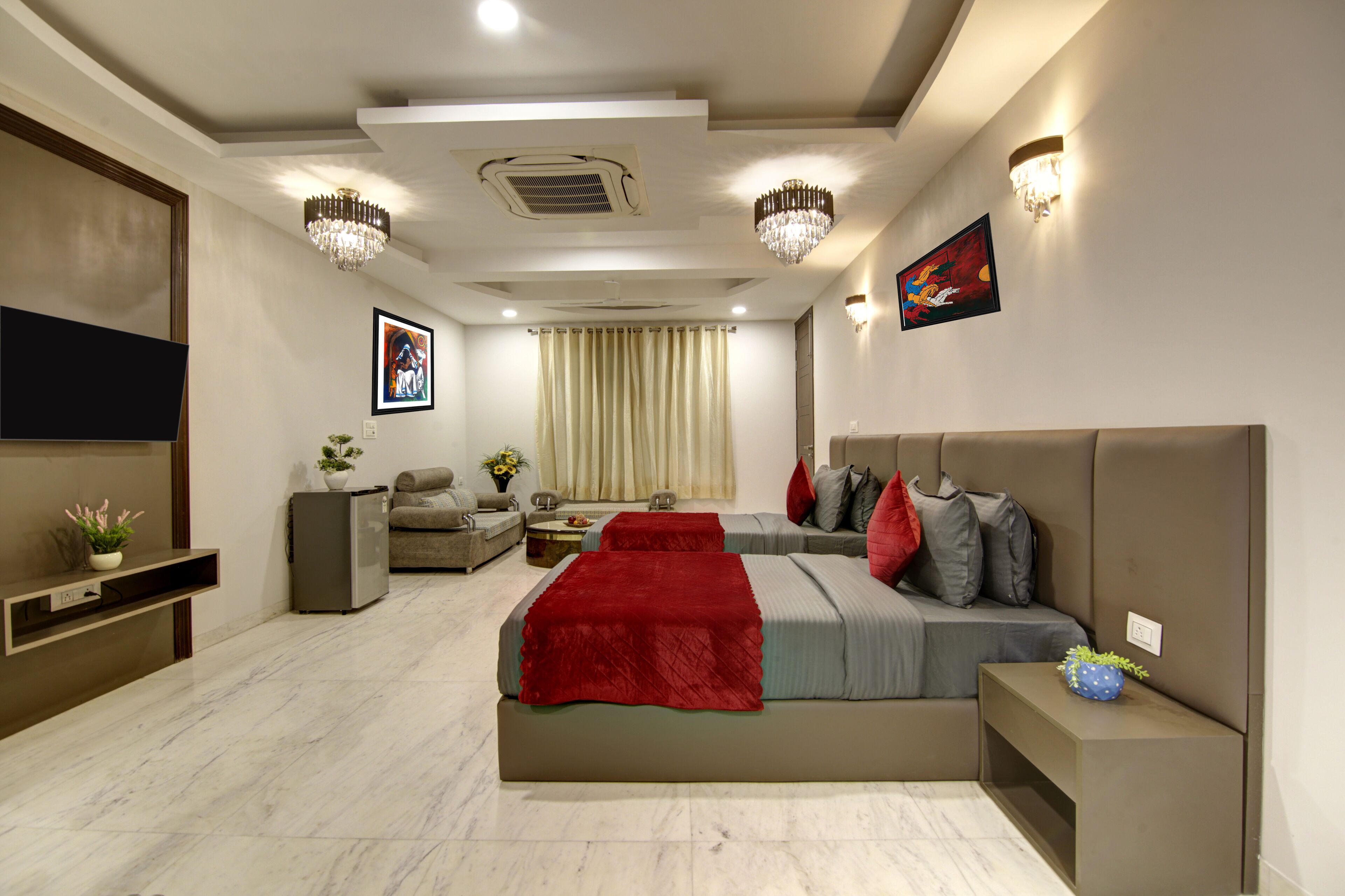 A modern bedroom with a large bed, a TV, a sofa, and a small table.
