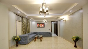 A spacious living room with a sectional sofa, a coffee table, and two decorative vases. - SONESTA LUXURY APARTMENT (New Delhi)