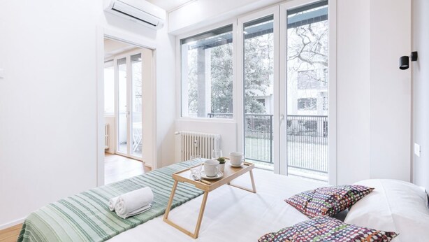 Une chambre d’hôtel lumineuse, avec un lit, une fenêtre et un radiateur.