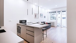Une cuisine moderne dotée d’un îlot central, d’un four encastré et d’un coin repas avec un canapé et des tabourets de bar.