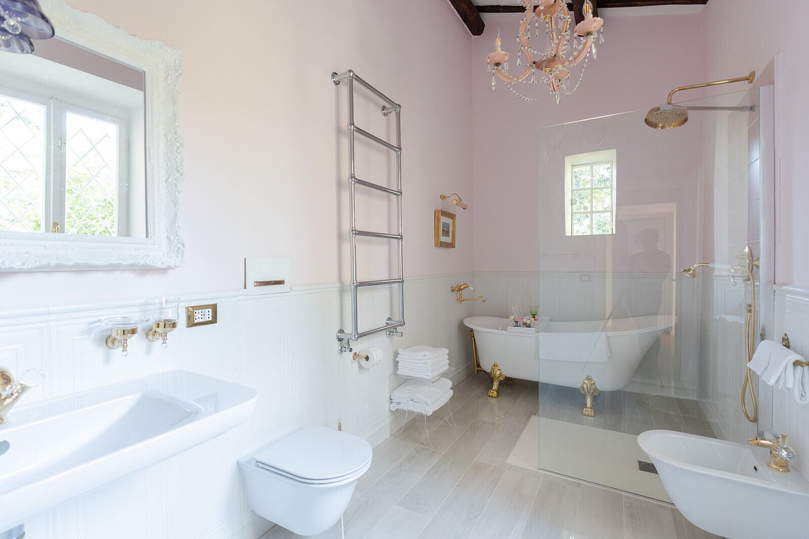 A bathroom with a bathtub, a shower, and a toilet. There is a chandelier above the bathtub.