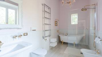 A bathroom with a bathtub, a shower, and a toilet. There is a chandelier above the bathtub.