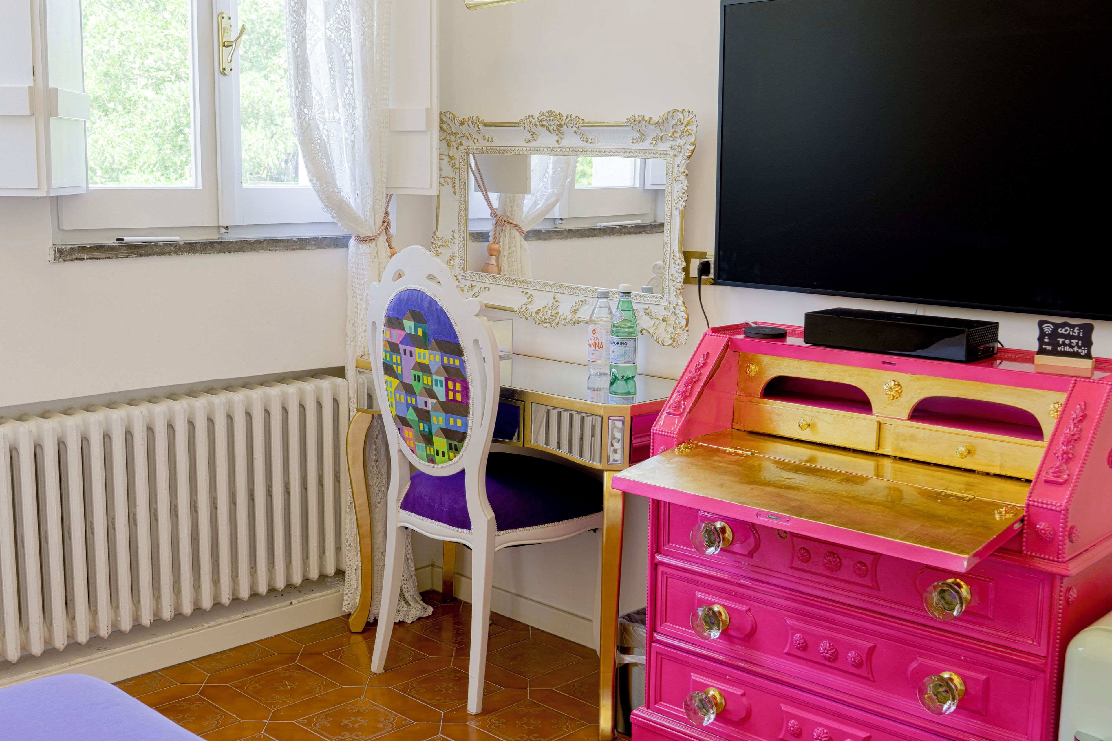 Una habitación infantil con televisión, cómoda, silla y radiador.