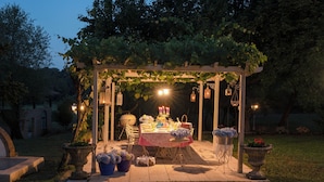 Un espace extérieur aménagé pour les repas, avec une pergola, une table décorée de bougies et des plantes en pot.