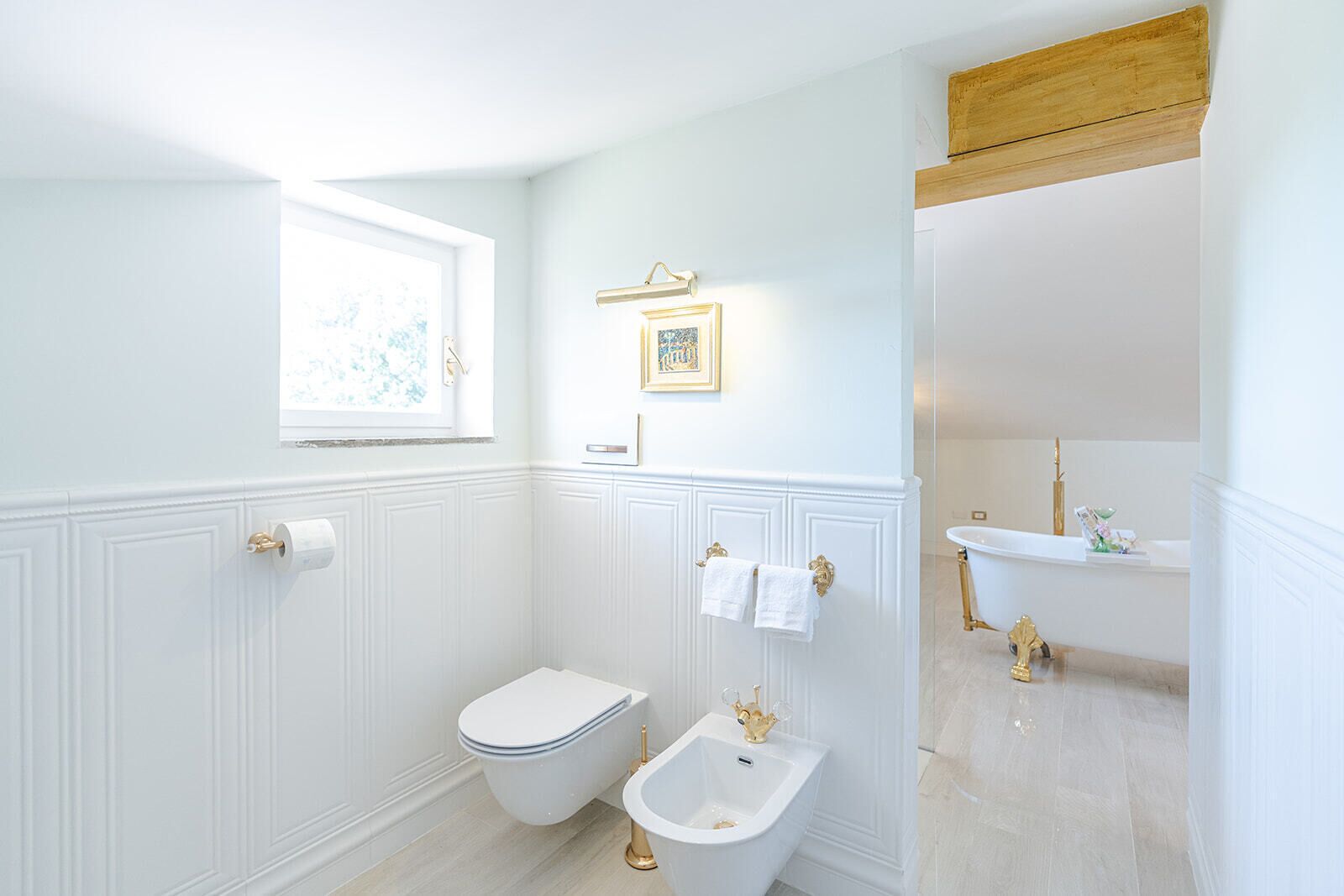 A bathroom with a toilet, bidet, and sink, all with gold fixtures.