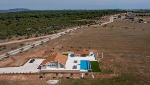 A large house with a swimming pool, surrounded by a vast open field and a road. - Charming villa Viliska with heated pool (Sveti Filip i Jakov)