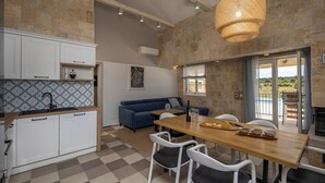 A modern kitchen with white cabinets, a blue sofa, and a dining area with a wooden table and chairs. - Charming villa Viliska with heated pool (Sveti Filip i Jakov)