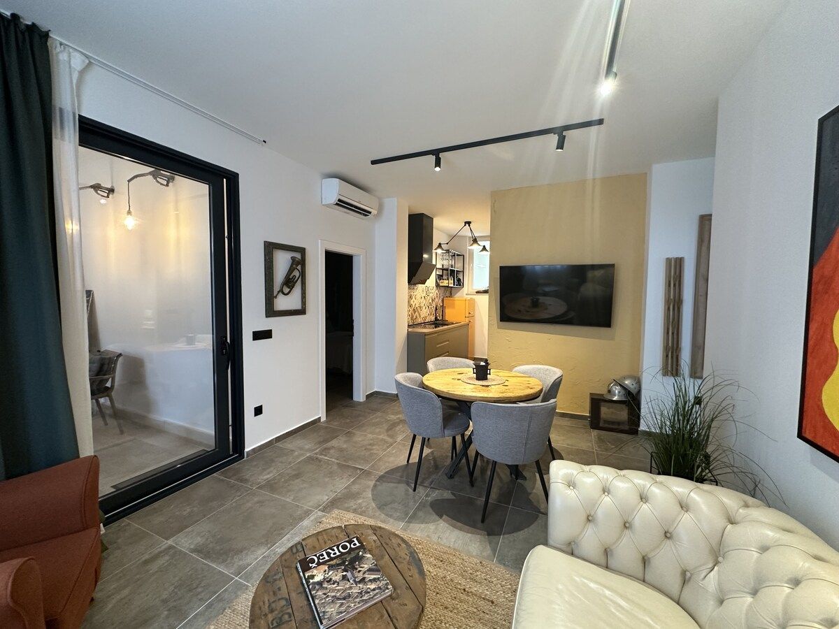 Een moderne woonkamer met een bank, een eettafel met stoelen en een keuken in de achtergrond.