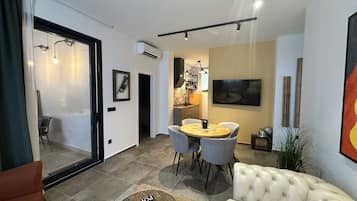 Een moderne woonkamer met een bank, een eettafel met stoelen en een keuken in de achtergrond.