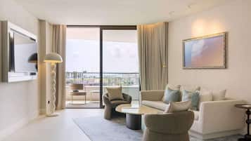 Un salon moderne avec un canapé, des fauteuils, une table basse et un téléviseur fixé au mur.