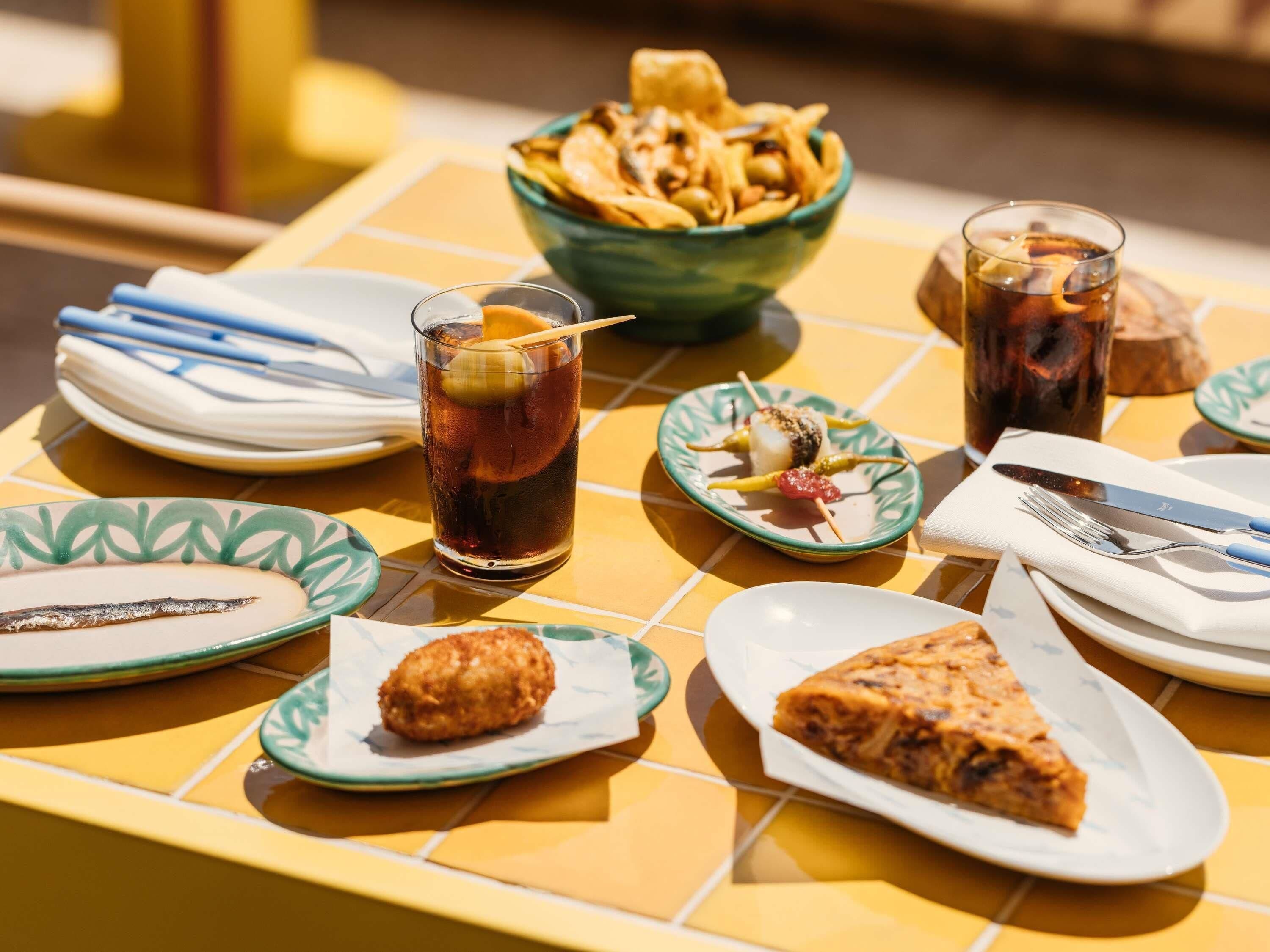 A table with food items, drinks, and cutlery.