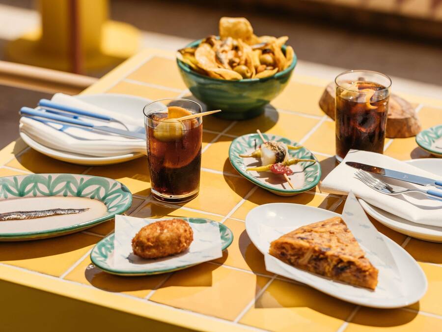 A table with food items, drinks, and cutlery.
