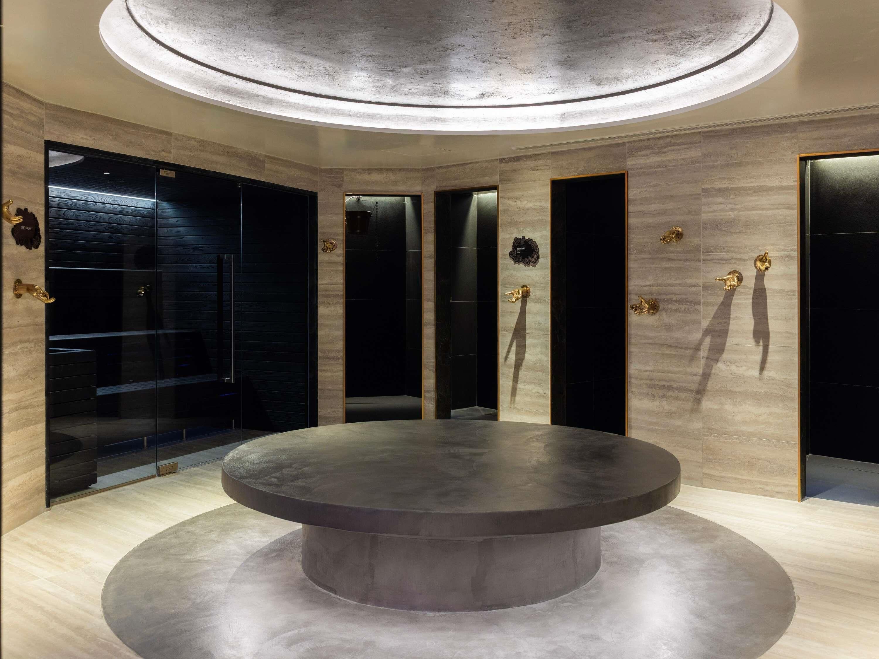 A circular seating area with a central table, surrounded by walls with vertical panels and gold accents.