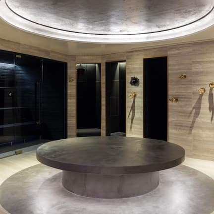 A circular seating area with a central table, surrounded by walls with vertical panels and gold accents.